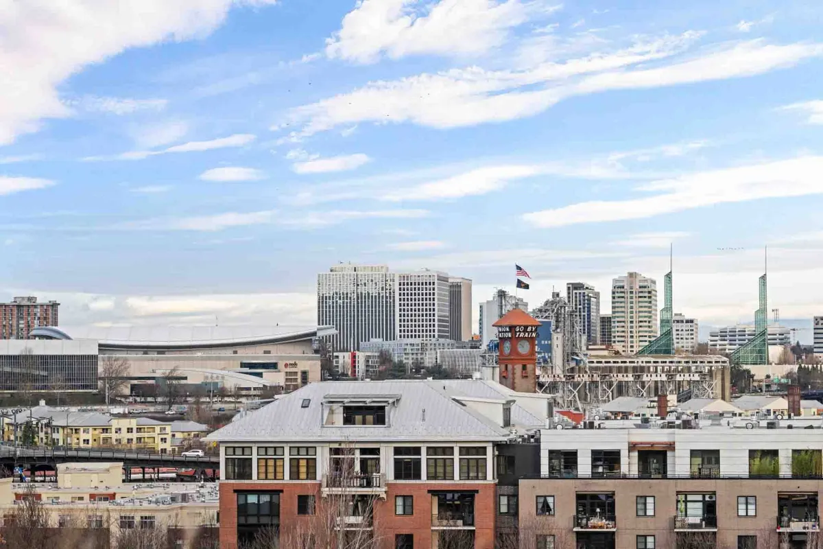 A panoramic view of the city skyline, including a historic clock tower, modern buildings, and green spires. The lively, urban setting visible from above hints at the penthouse’s elevated vantage point and connection to the vibrant downtown environment.