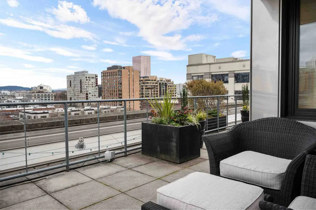 A stylish outdoor seating area with plush furnishings, planters, and a sweeping, unobstructed view of the city skyline. The terrace is bathed in natural light, capturing the contemplative mood of sunset. Perfect for relaxing or hosting intimate gatherings while enjoying panoramic vistas.