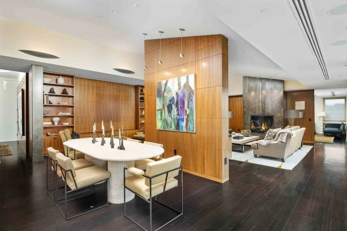 A contemporary dining area with an art piece on the wall, a dining table set with candles, and a fireplace, creating a warm, welcoming space. The atmosphere is inviting, ideal for gathering after events or celebrating special occasions.