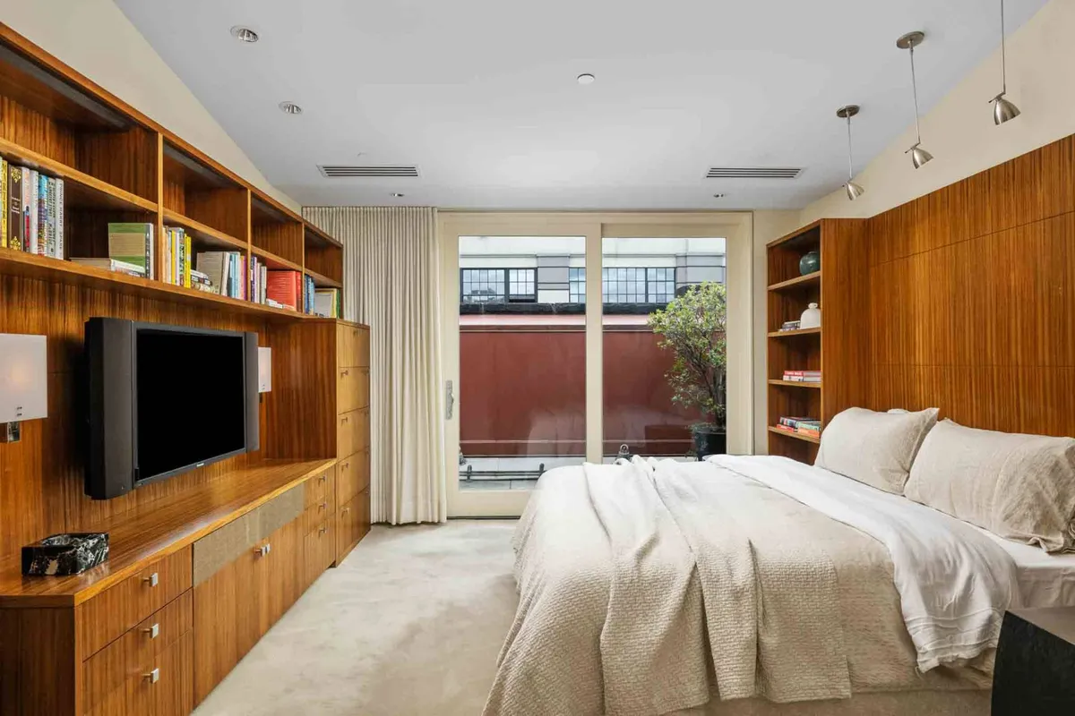 A serene media room with a bed, bookshelf, and windows letting in gentle light. The space is versatile, suited for reading, watching TV, or serving as an additional cozy sleeping area for guests.